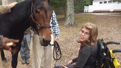 Photo of young woman in wheelchair next to a horse
