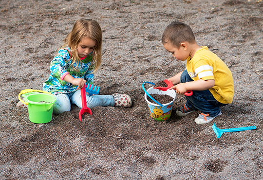 two children playing outside in sandbox