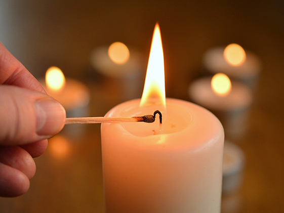 hand holding match to light candle