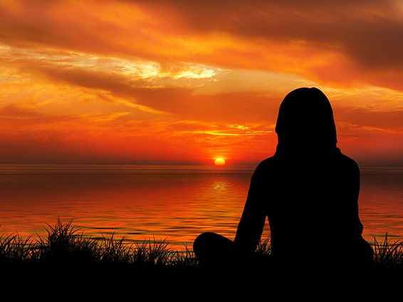 silhouette person sitting facing sunset