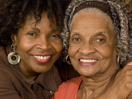older adult family member and caregiver smiling
