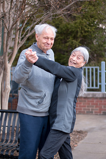 Male and female Adult Day Health Care participants in a ballroom dance pose