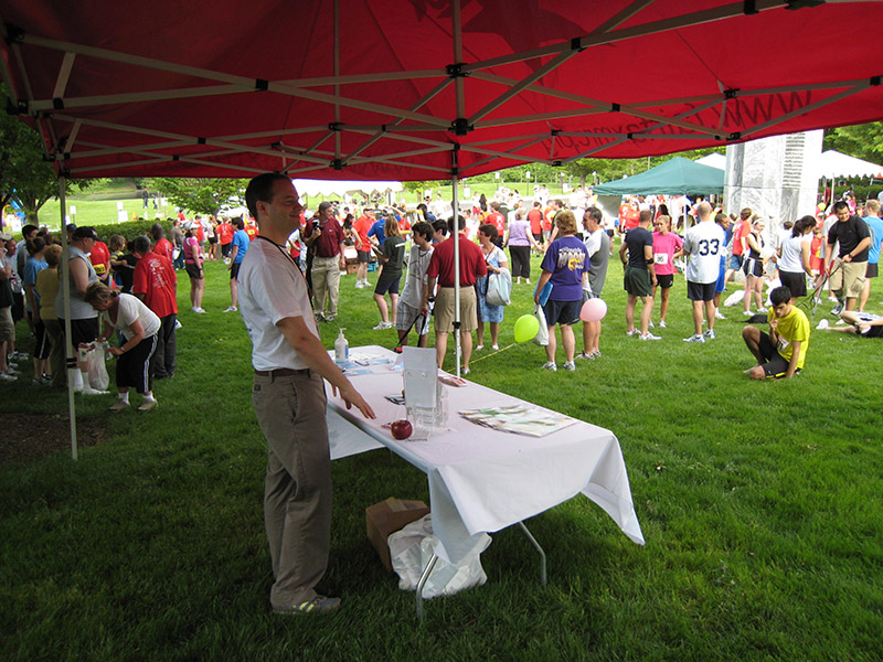 Volunteer staffs an MRC table at an outdoor event