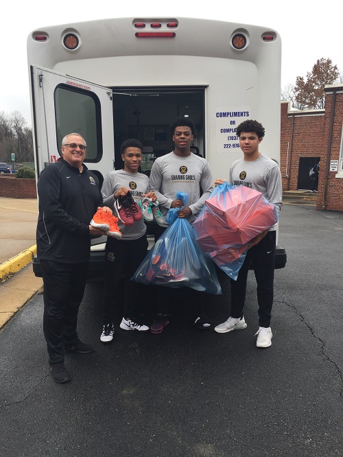 Coach and students pose with donated shoes.