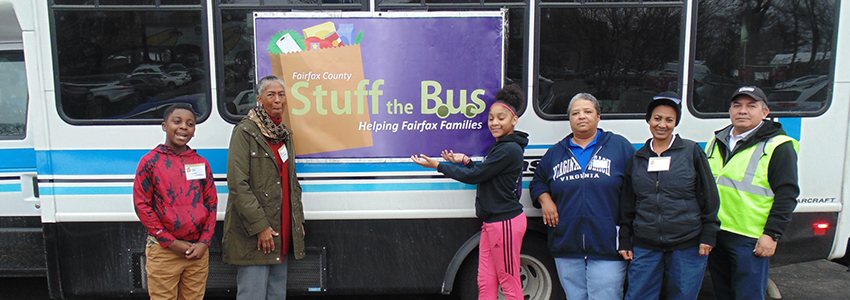 Volunteers pose in front of a Fastran bus filled with donated food.