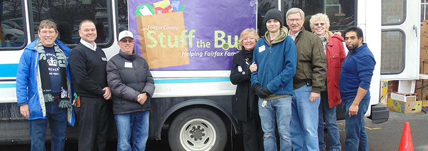 Volunteers pose in front of a Fastran Bus filled with donated food.
