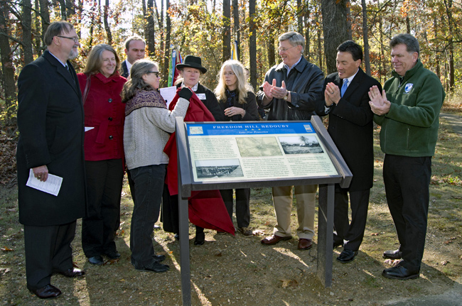 Dignitaries unveil a sign at Freedom Hill's dedication ceremony