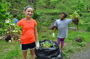 Two young girls display their bags of removed invasive plants