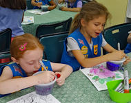 Two Girl Scouts work on crafts at a table
