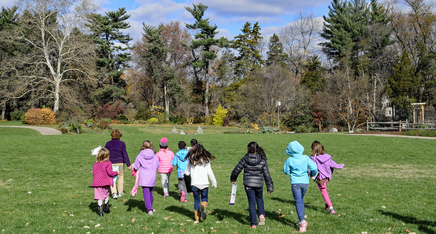 Girl Scouts run across a grassy field at Green Spring