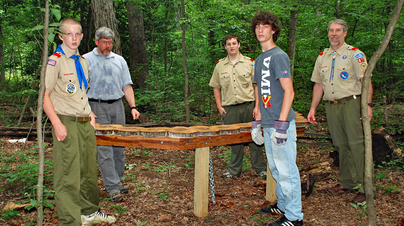 Several scouts stand with a bench they built for Nature Playce at Hidden Oaks