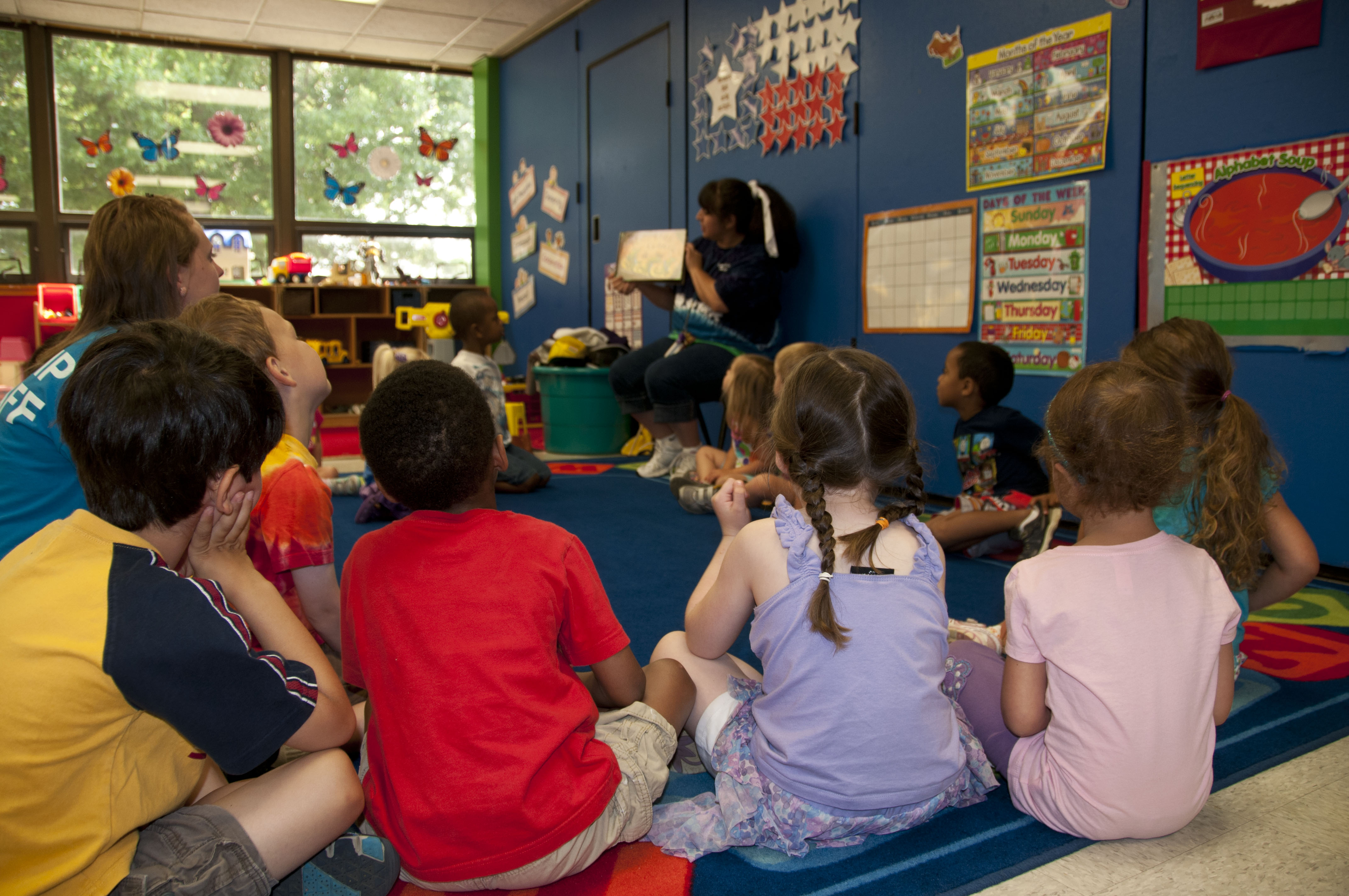 Preschool teacher reading a book to students