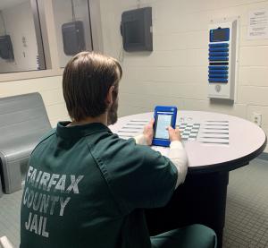 Inmate reads from tablet in the quiet room of cell block.