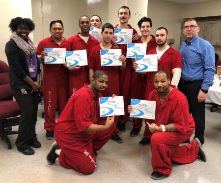 Nine kitchen crew inmates, holding certificates, are with two Aramark staff.
