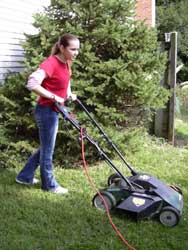 girl cuts grass with electric mower