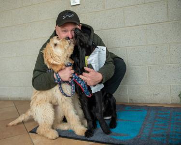 man with two dogs licking his face