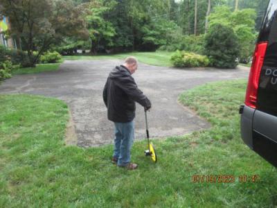 man measuring yard and driveway