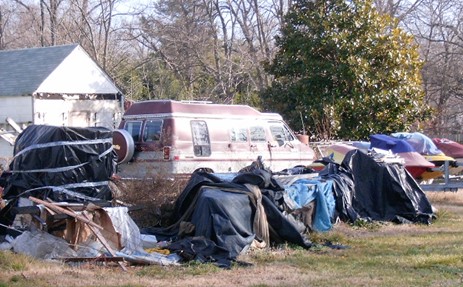 van, jet skis and other tarped items sitting in yard
