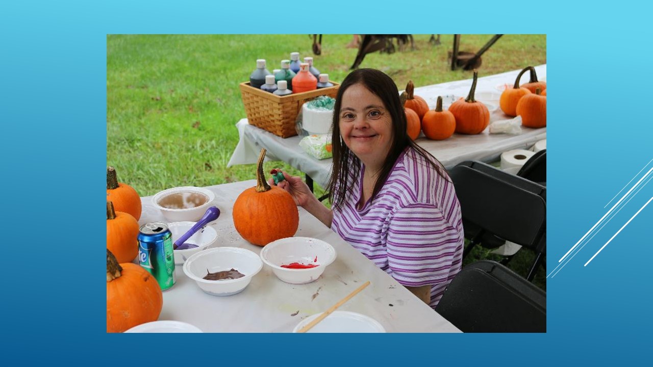 Photo of woman with developmental disabilities paining a pumpkin