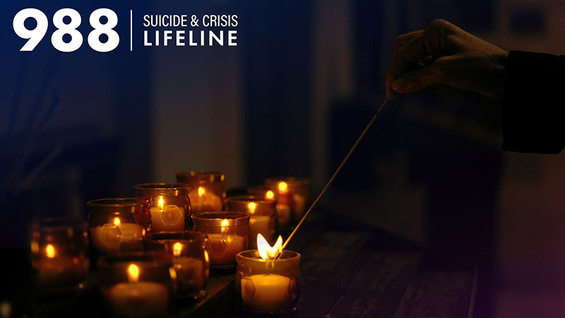 A row of candles solemnly lit in remembrance. The logo for the 988 Suicide and Crisis Lifeline is in the top left of the image.