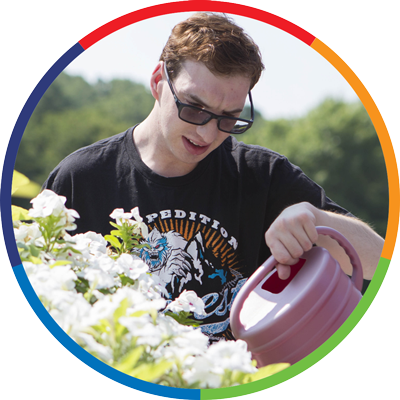 a man with a watering can watering flowers