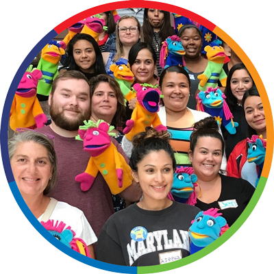 a group of individuals all with brightly colored hand puppets together smiling