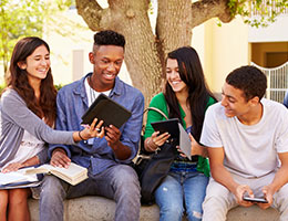 A group of young people sitting on a bench and smiling while conversing.