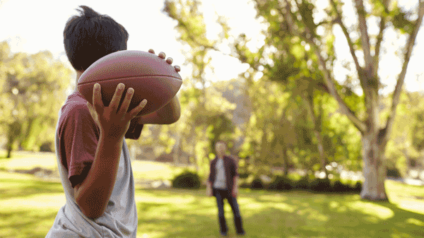 Boy throwing football to man