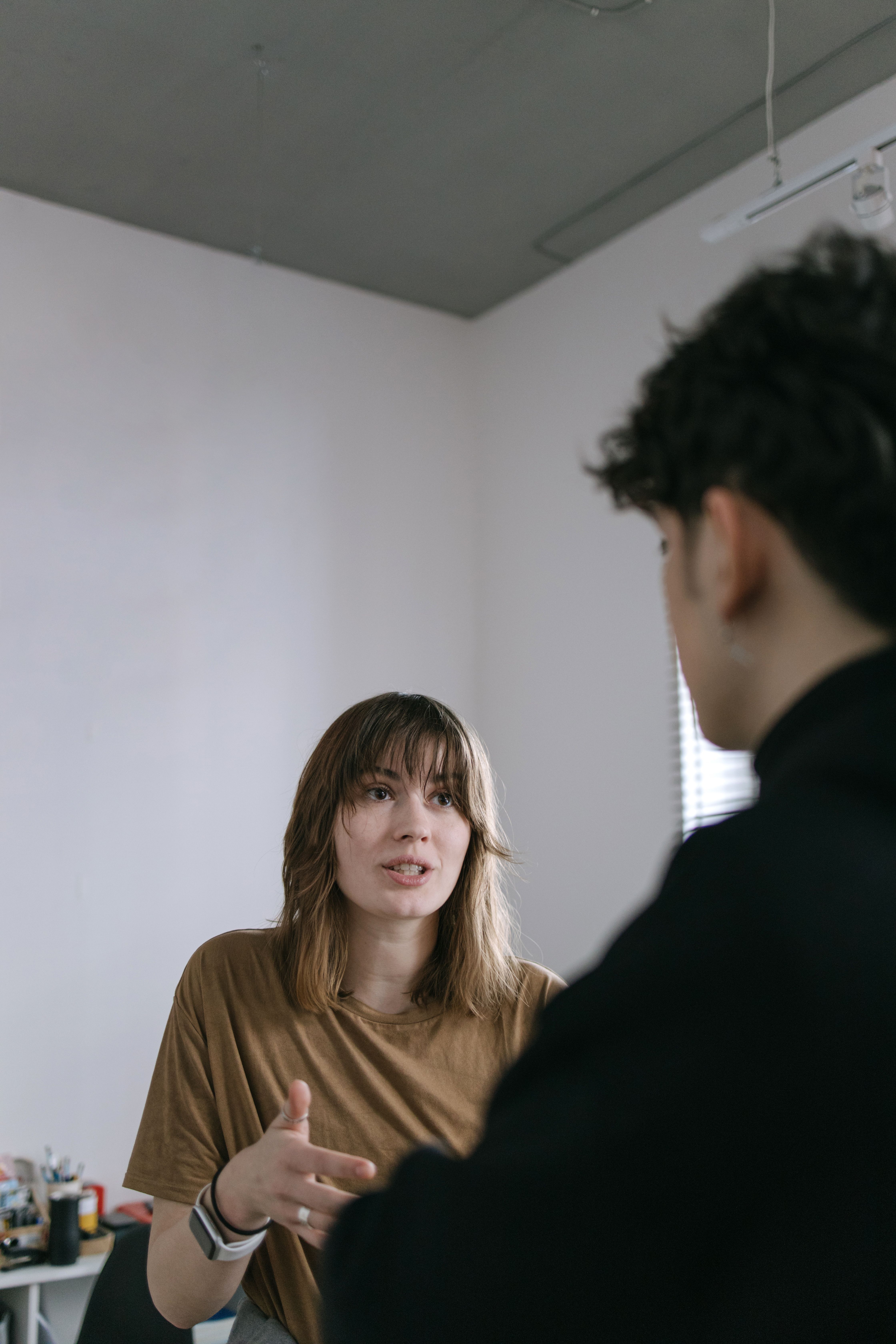 A woman talks to a man sitting in front of her.