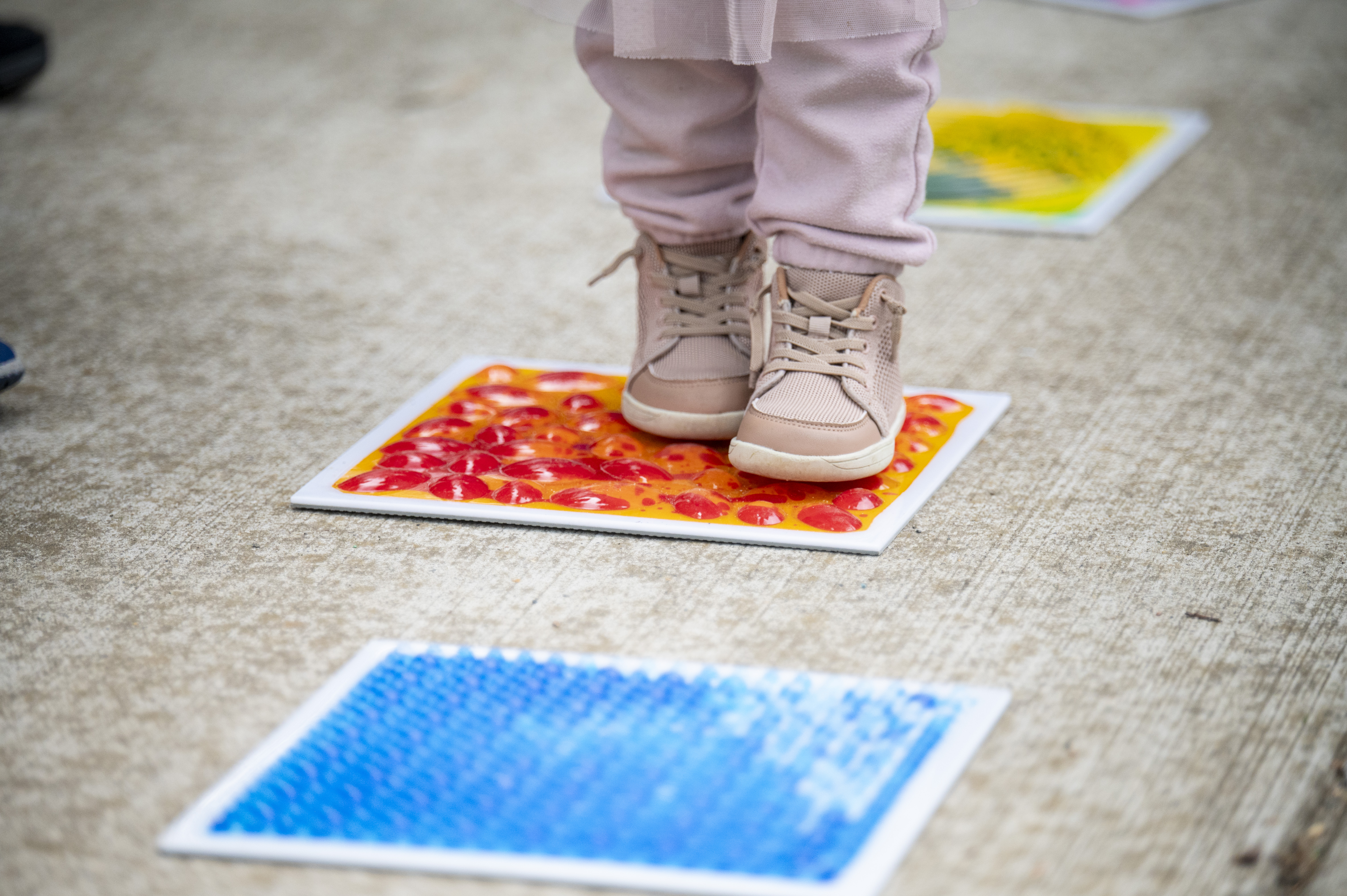 A young child's feet are seen walking across colorful tiles