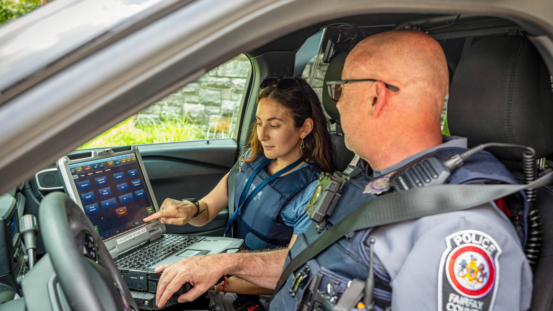 a police office and a behavioral health specialist talk to a woman seated on a park bench and give her an info card