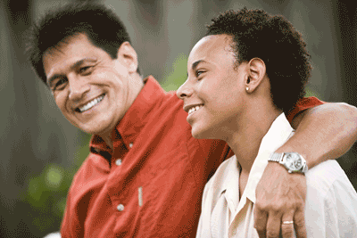 Photo of smiling father with arm around teen son