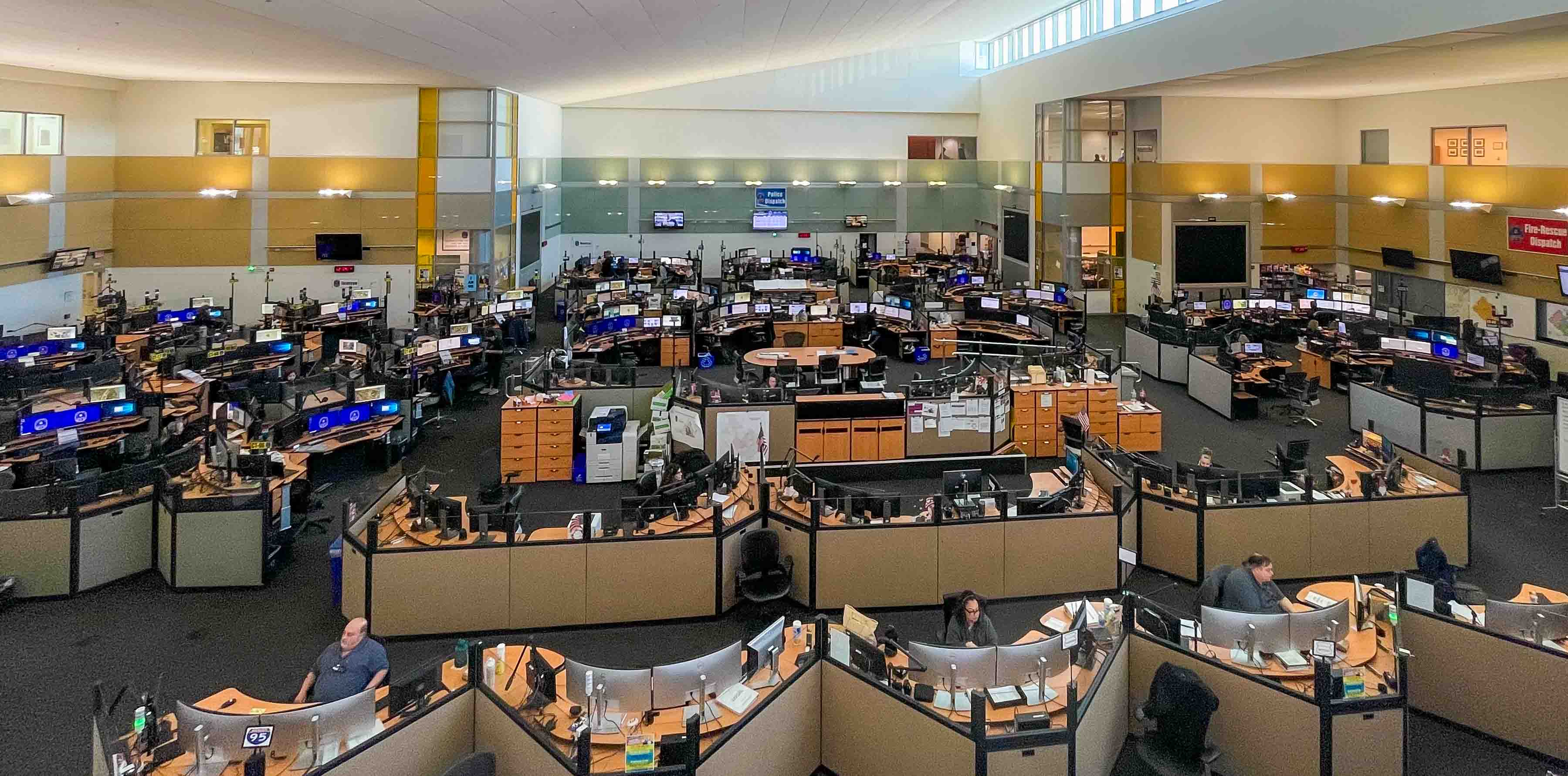 looking down on many desks with computers and phones at 9-1-1 call center