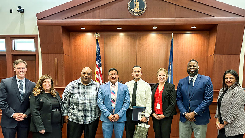 A group of men and women in professional attire together in a courtroom.