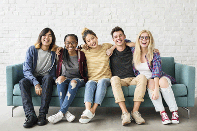 Photo of teens smiling and sitting on a couch