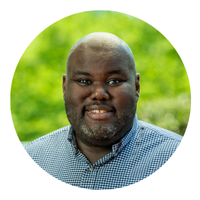 headshot of man with green background and blue shirt