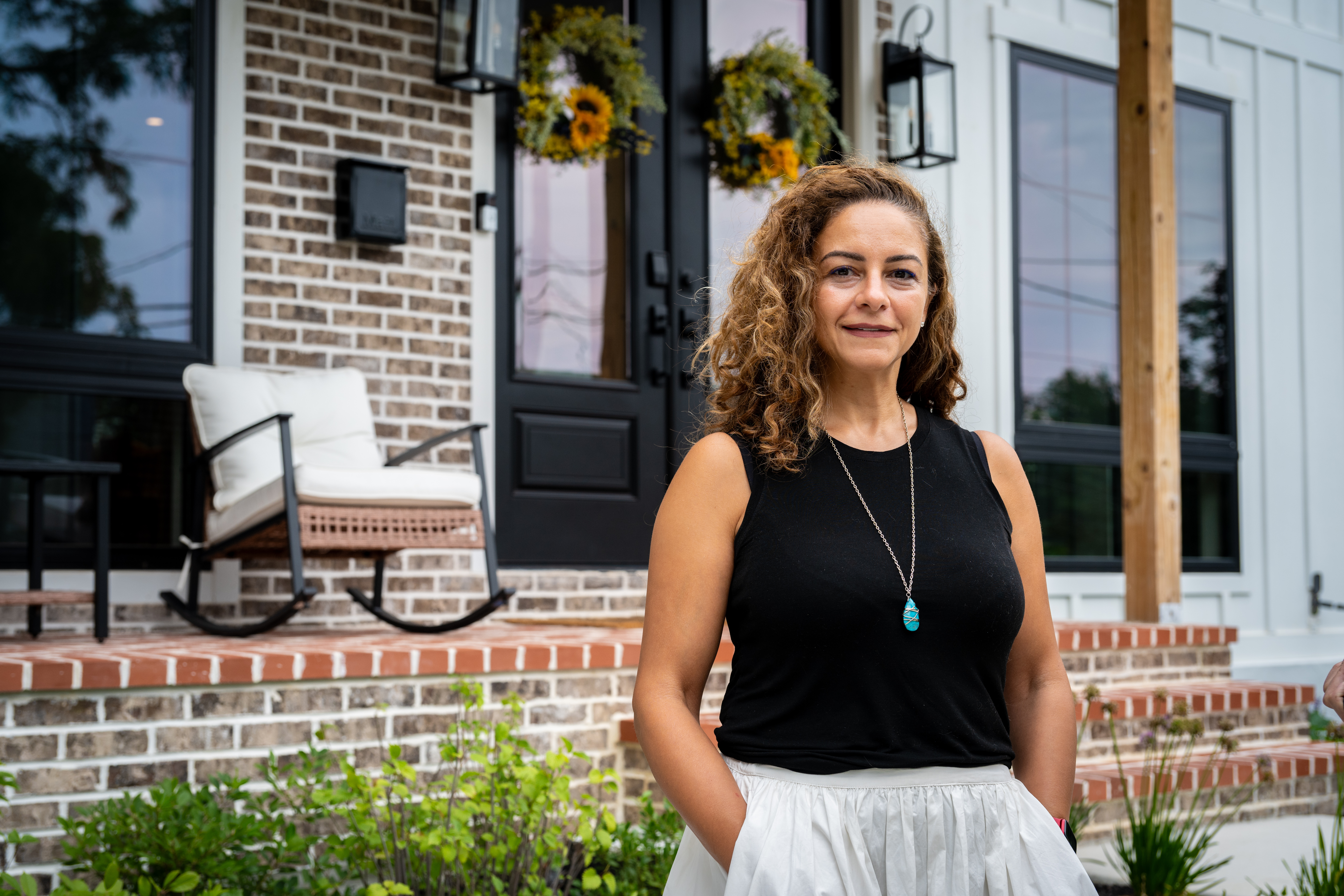 photo of Mona in a black shirt posing in front of her home