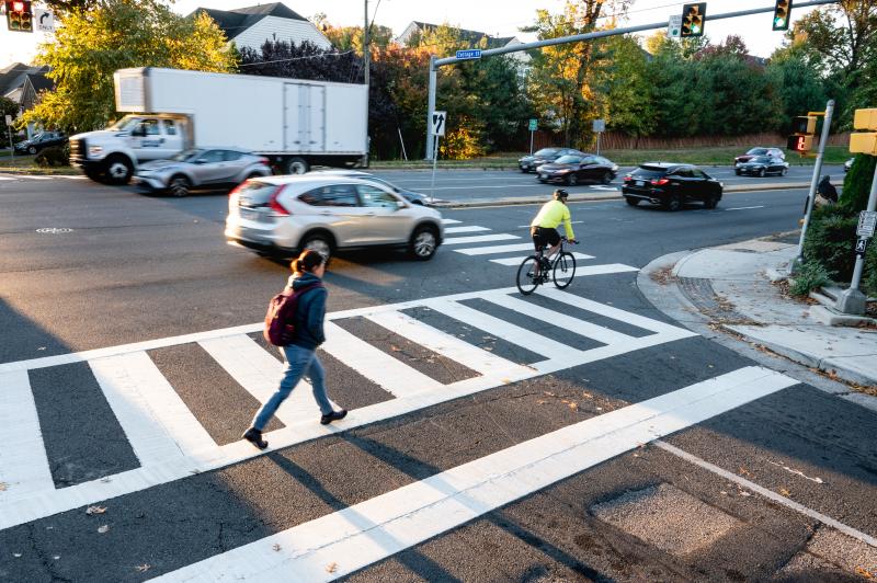 person biking and person walking through an intersection