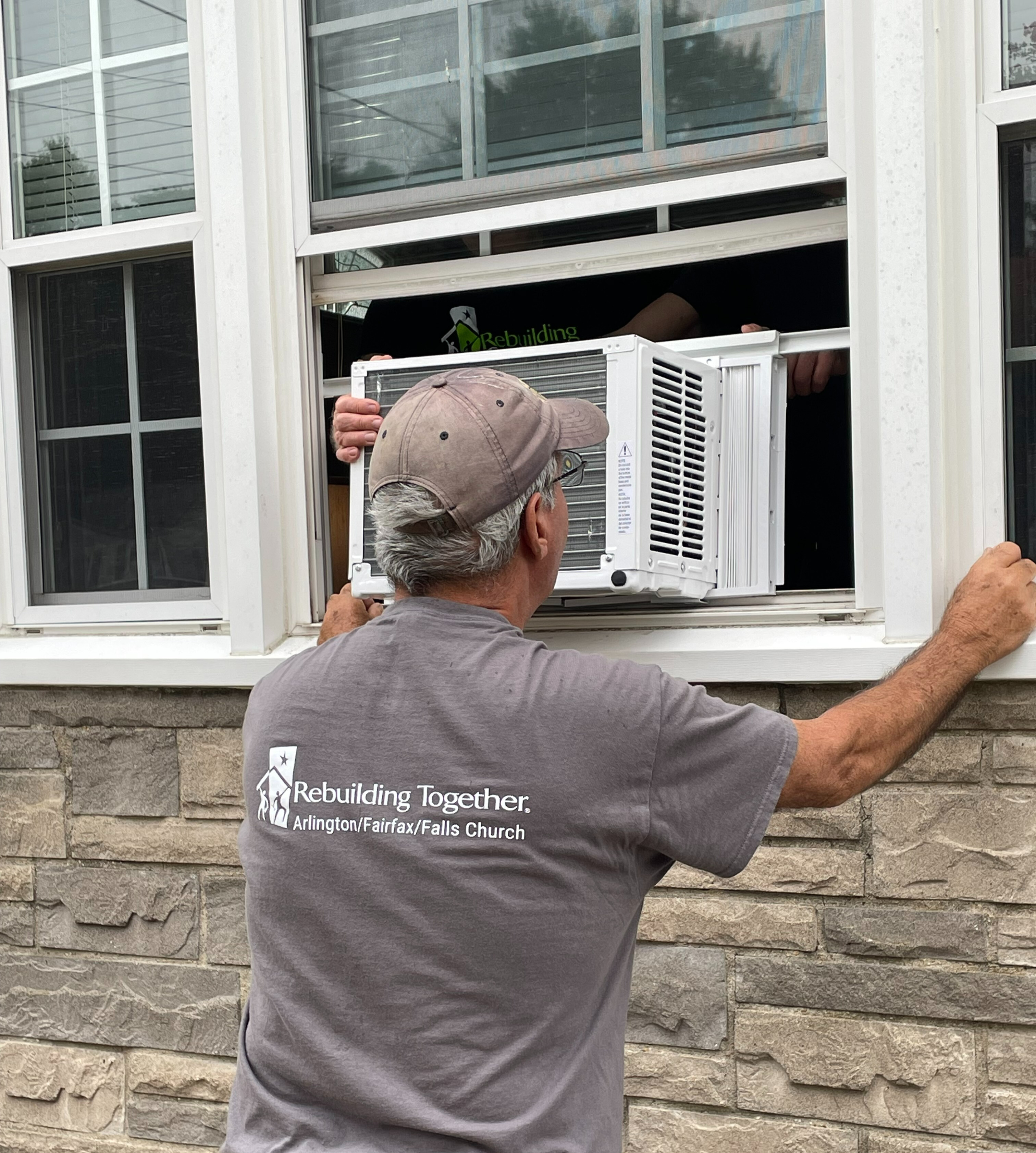 Rebuilding Together volunteer installing a window air conditioning unit