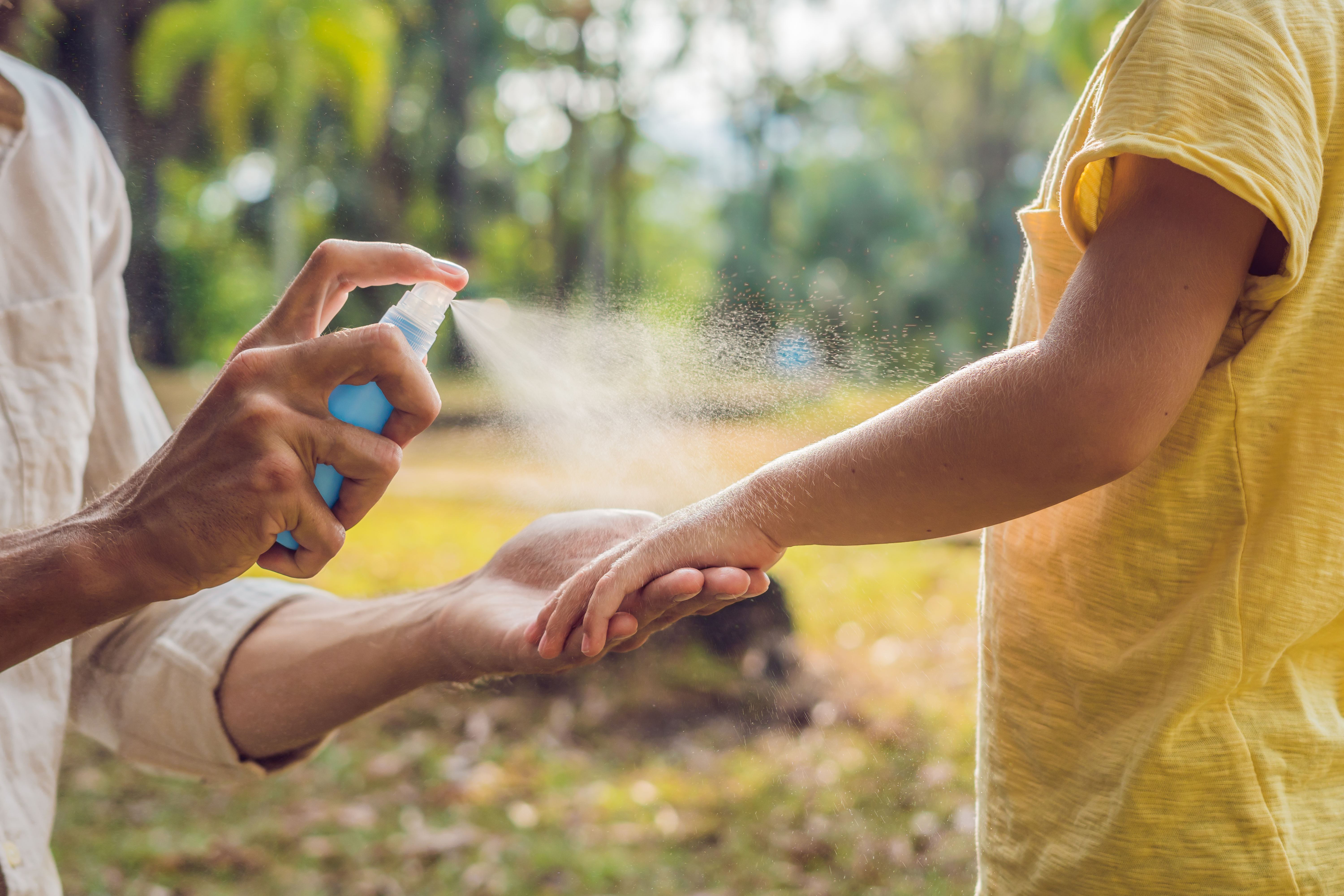 parent spraying bug spray on a toddler