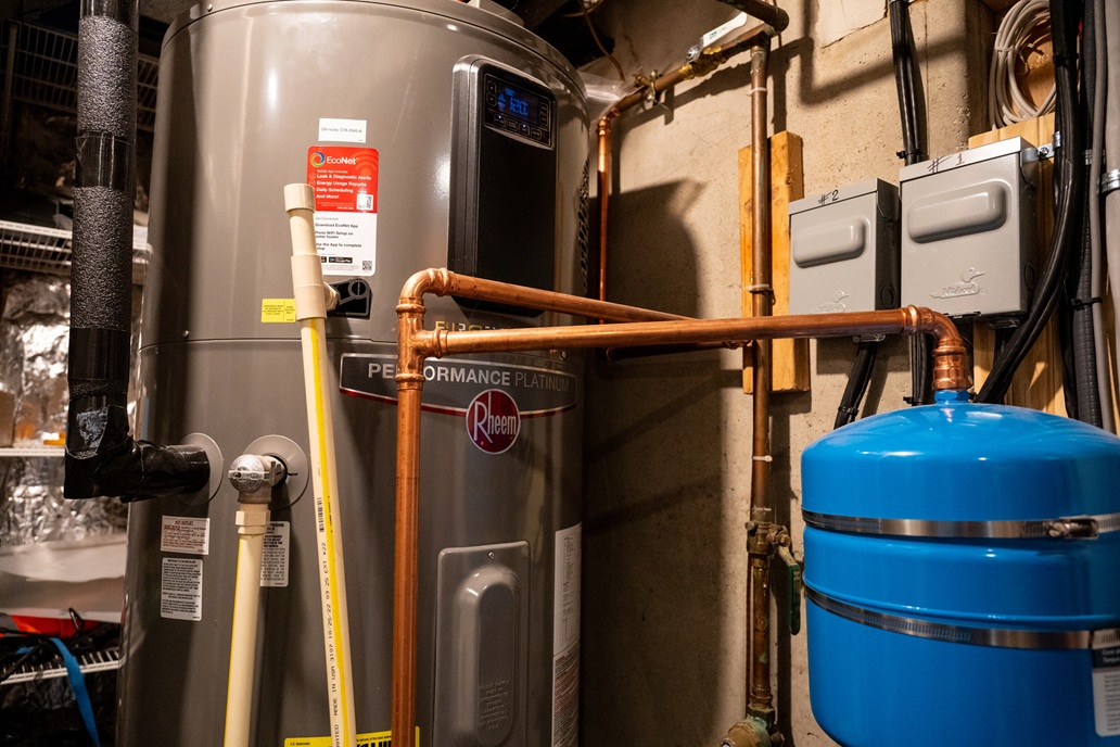 Close-up of a heat pump water heater with connected pipes and equipment.