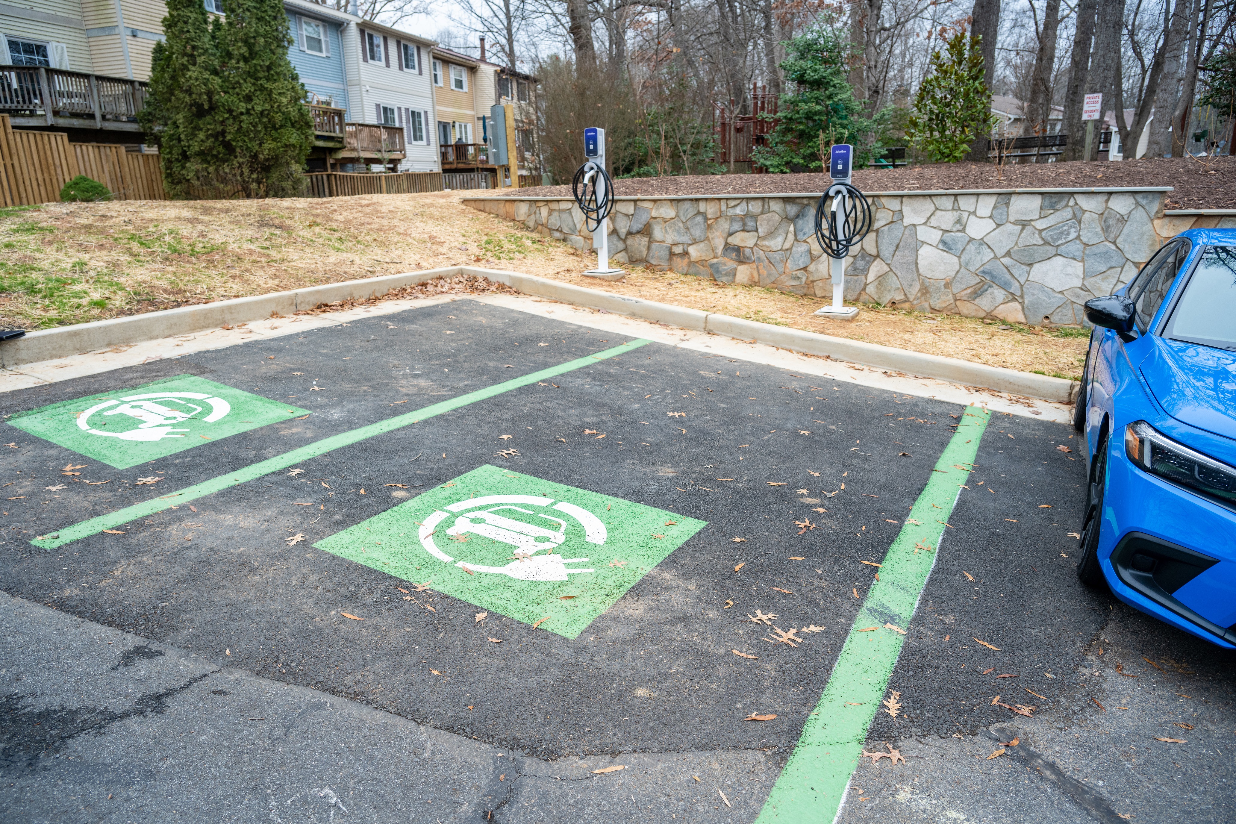 Two designated electric vehicle charging parking spaces with green markings and nearby charging stations, located in a residential area