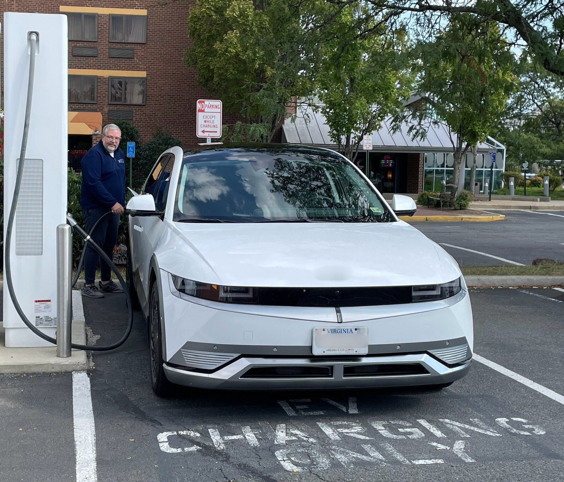 Chris Miles standing at an EV charger, plugging in car 