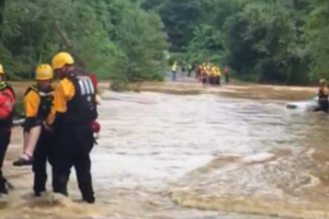 photo of rescue crew in flooded street with car in the background