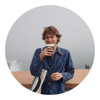 photo of sam holding coffee with a foggy landscape behind him