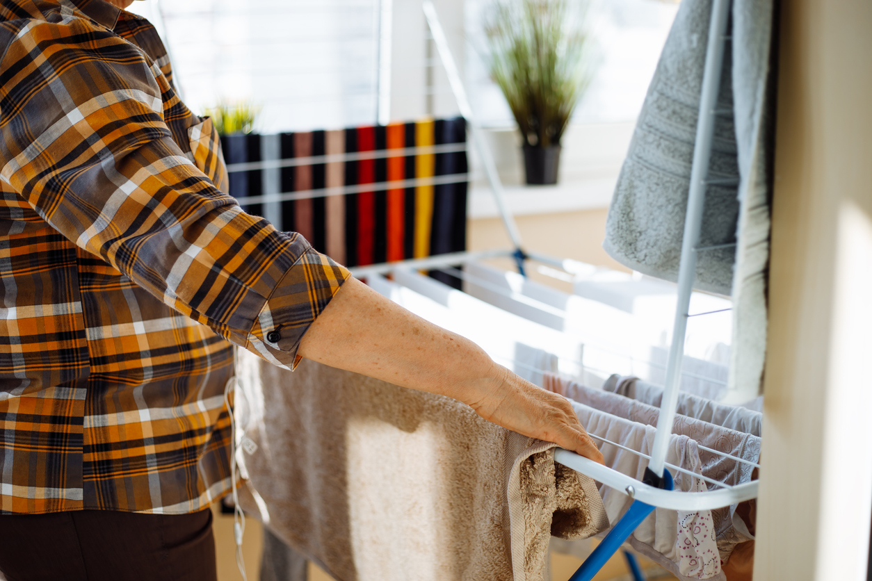 woman setting up clothes on an indoor drying rack