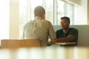 teen boy sitting at table with adult
