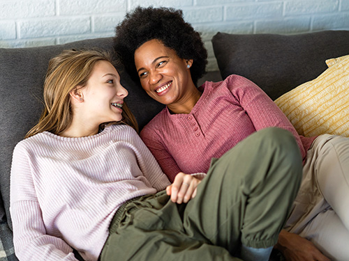 woman and teen girl smiling on couch