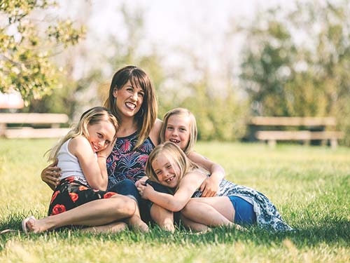 adult and three children sitting on grass