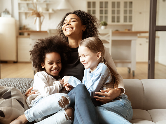 adult and two children sitting on sofa laughing